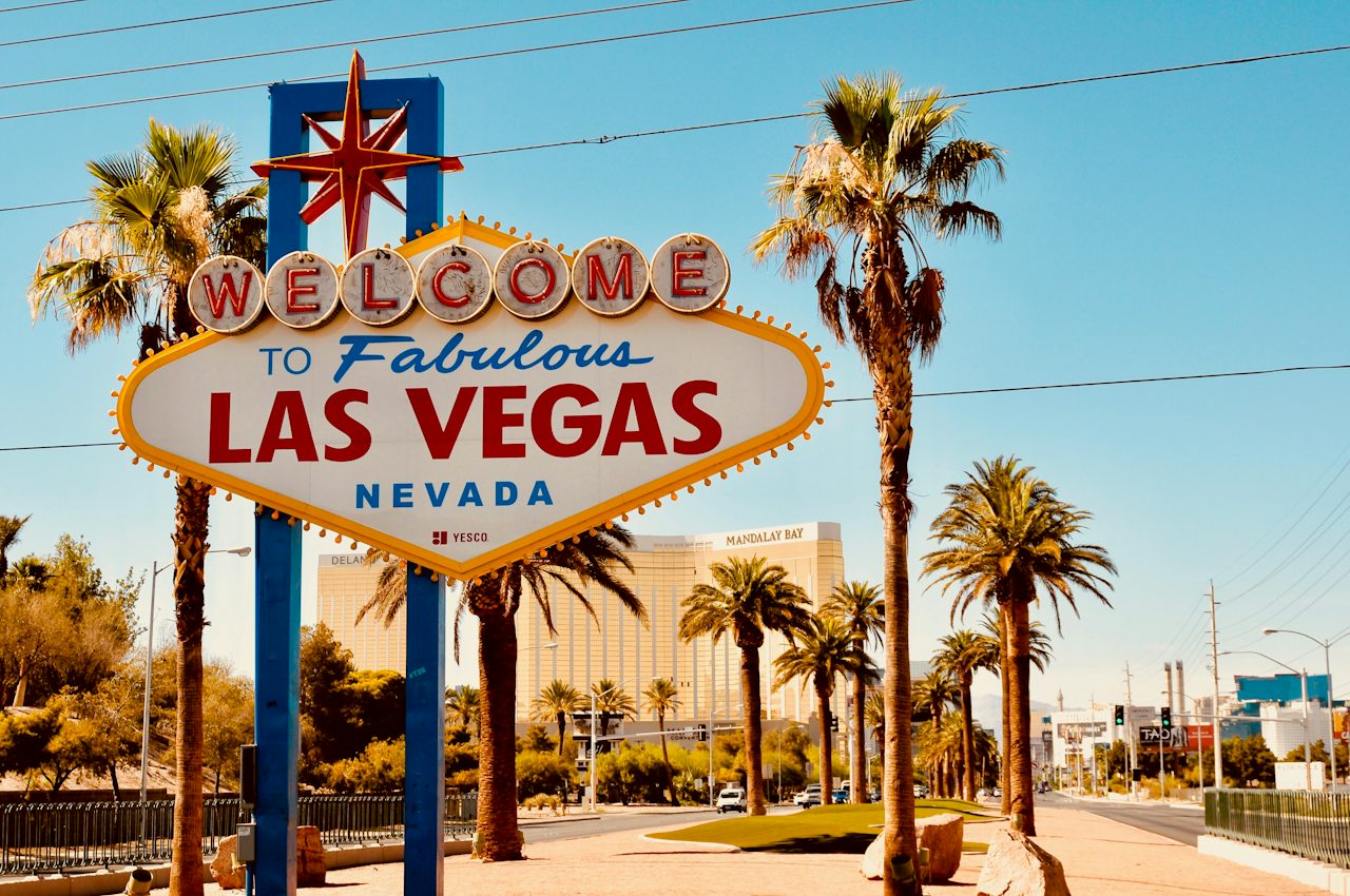 The Welcome to Fabulous Las Vegas sign under palm trees by day